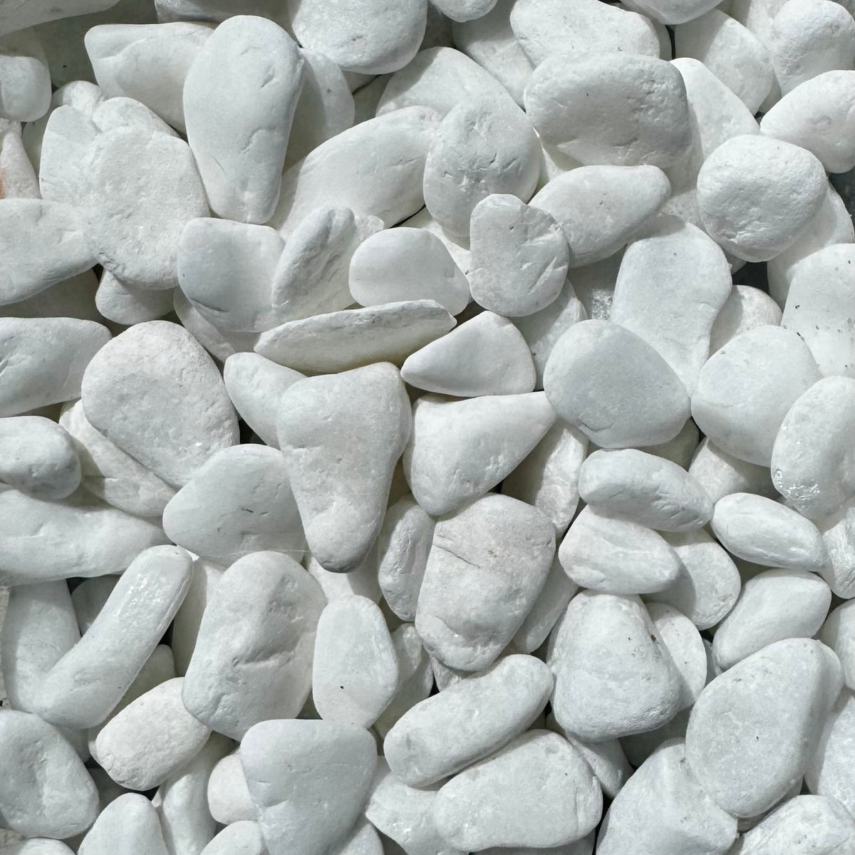 A close-up pile of smooth, rounded white decorative stones or pebbles filling the frame.